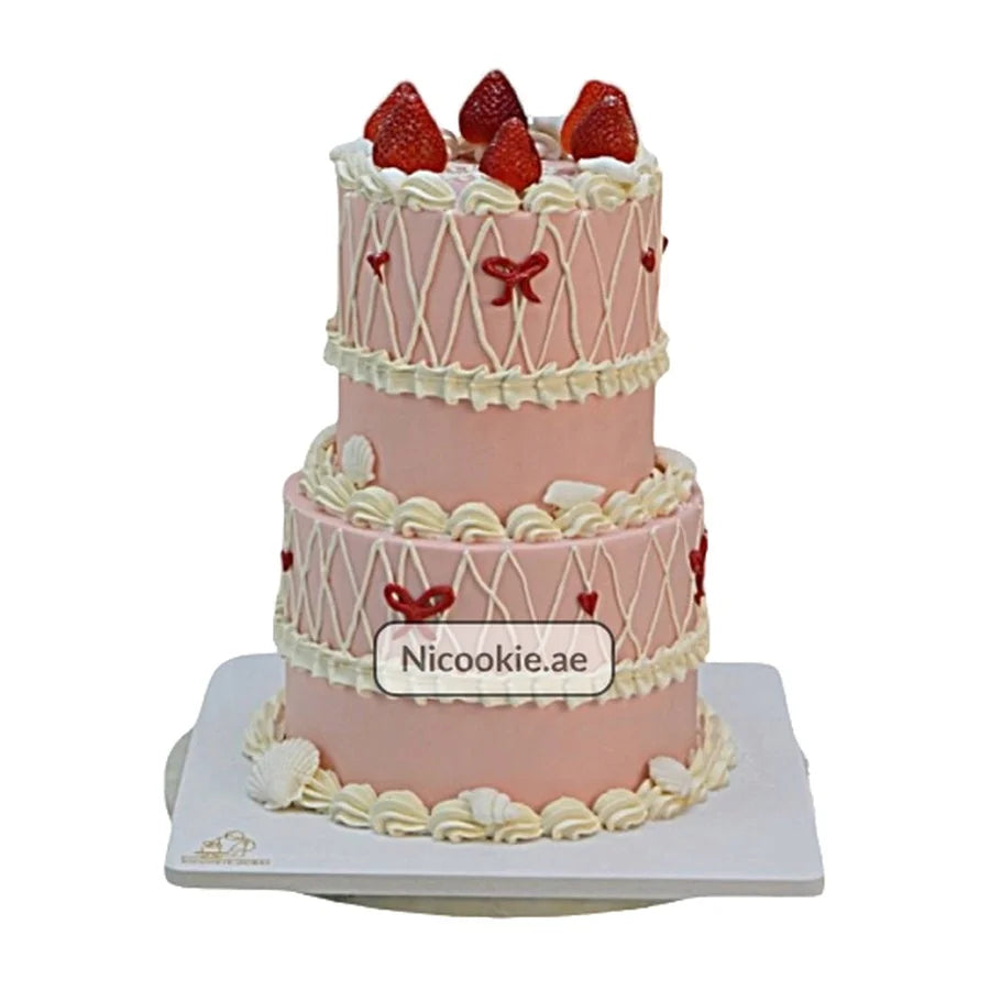 Two-tier pink cake with strawberries and white frosting.