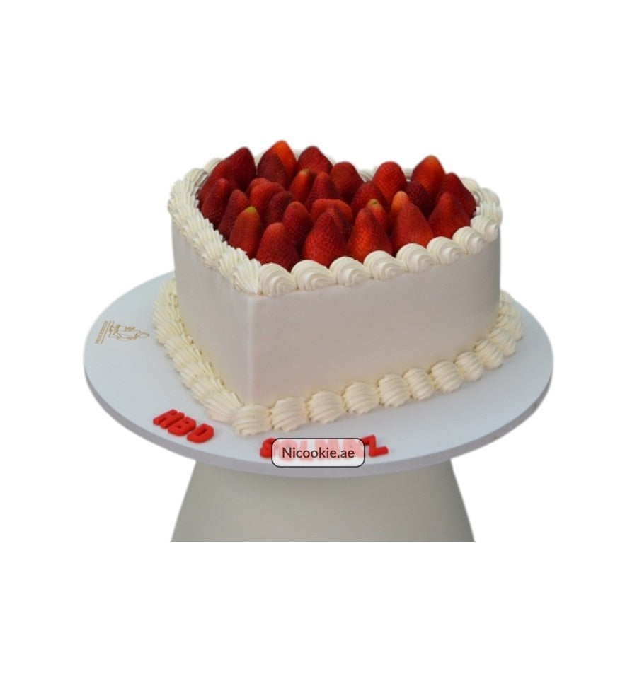 Heart-shaped cake topped with fresh strawberries and cream frosting.