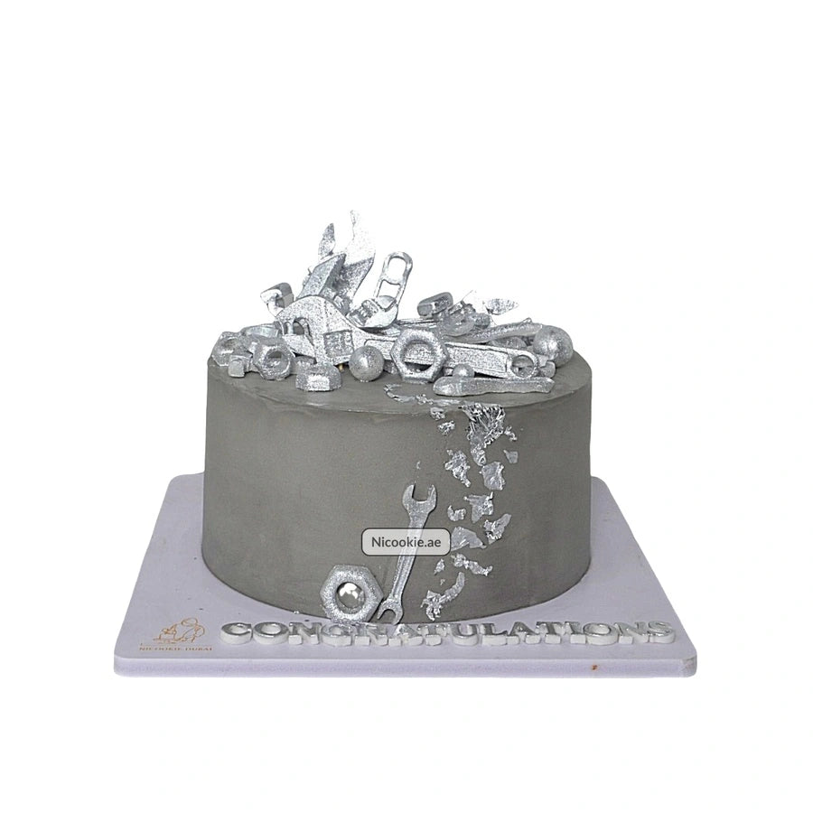 A gray cake decorated with silver tools and nuts.
