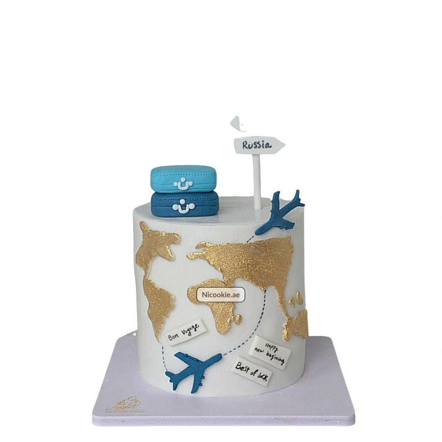 A travel-themed cake decorated with a gold world map, airplanes, and luggage.