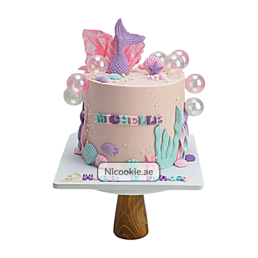 A mermaid-themed cake with seashells, bubbles, and the name Michelle.