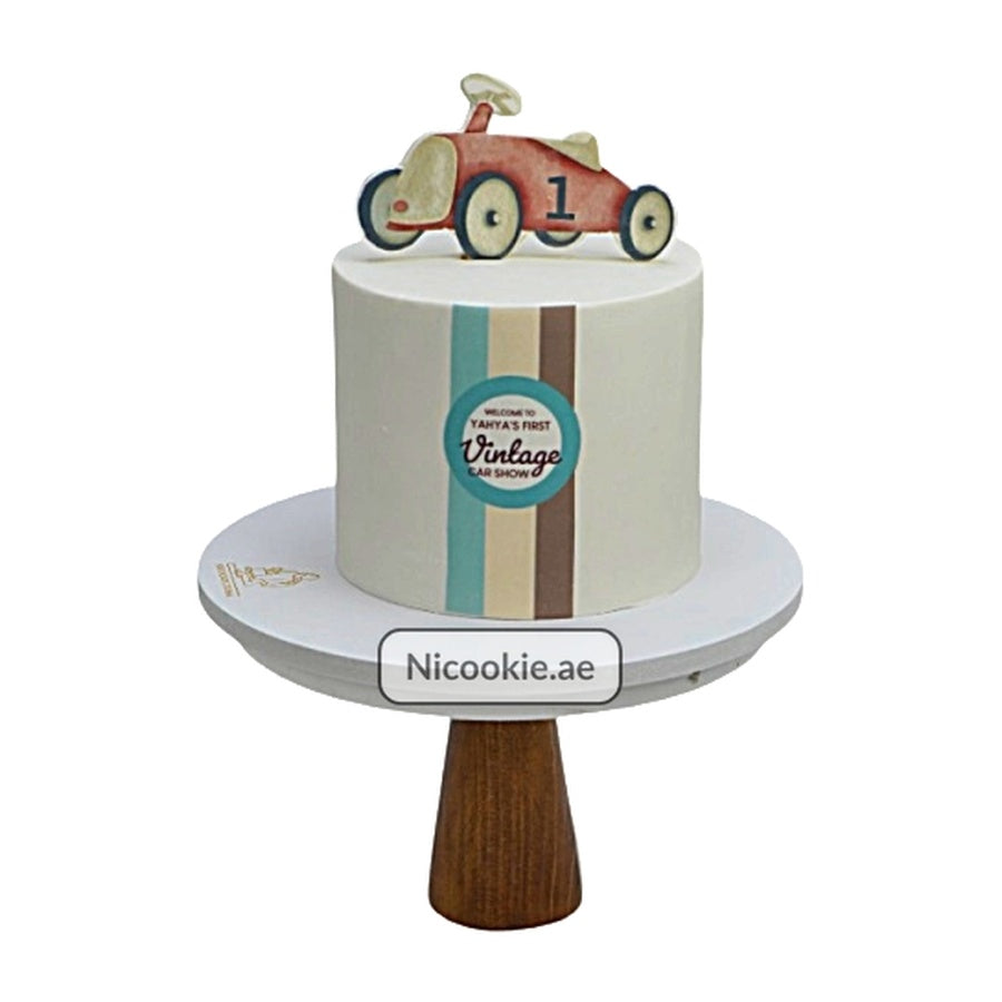 Vintage car first birthday cake with a toy car topper and retro stripes.