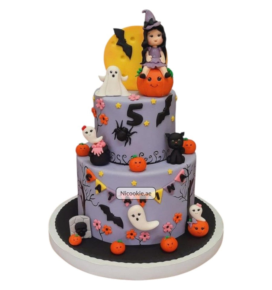 A two-tier Halloween cake with a witch, ghosts, pumpkins, and bats.