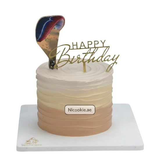 A birthday cake with ombre frosting and a paragliding topper.